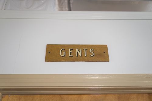 Free A rustic wooden 'Gents' sign mounted above a door, indicating a men's restroom. Stock Photo