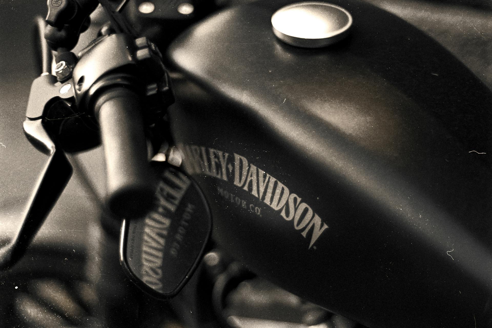 Vintage-style close-up shot of a motorcycle fuel tank with visible handlebars.