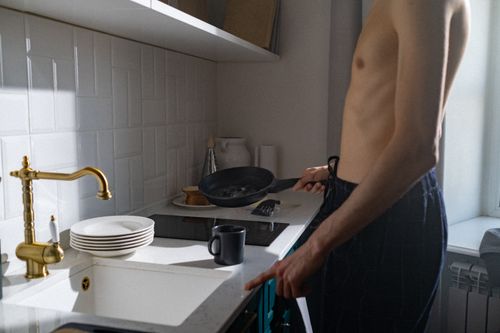Free A young man prepares breakfast in a sunlit kitchen, capturing a daily routine moment. Stock Photo