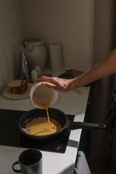 A man making an omelette in a modern kitchen, highlighting a morning routine.