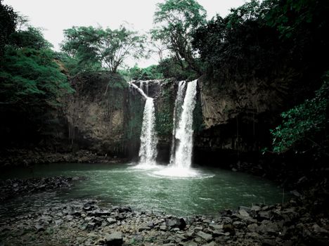 Beautiful waterfall cascading into a serene pool in a lush green forest.