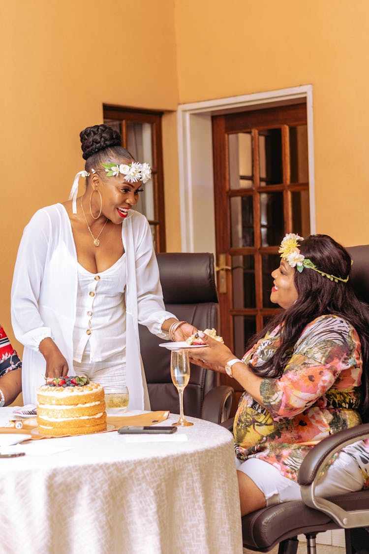 Women Near A Table With Cake Wearing Flower Crowns