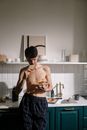 Topless Man in Blue Shorts Standing in Front of Sink