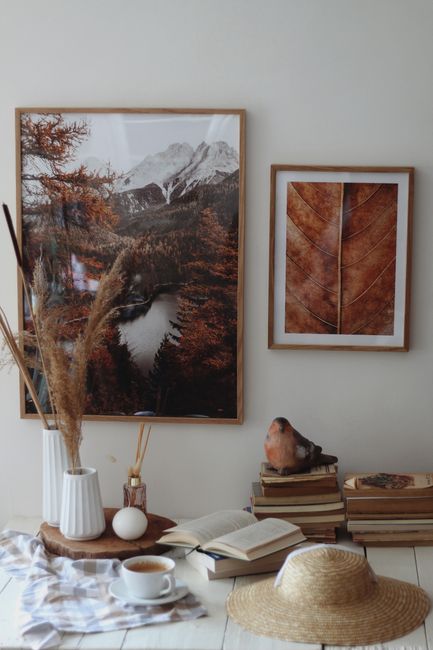 Warm indoor setting with books, a hot drink, and autumn-themed art for cozy reading.