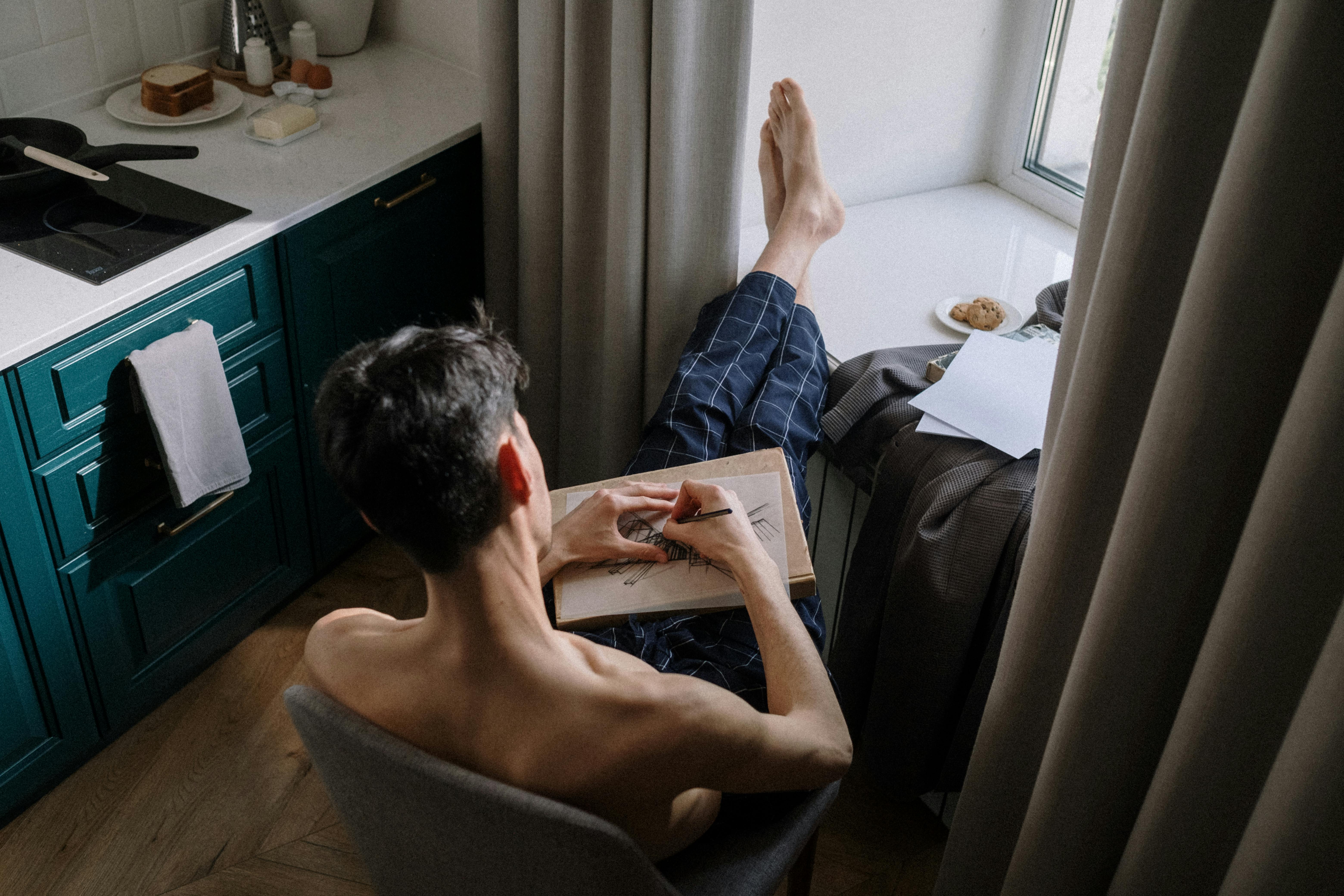 adult man sitting on chair in room and writing