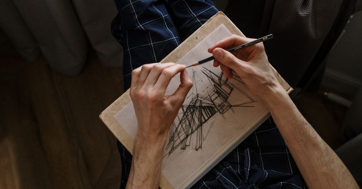 A person drawing abstract lines on paper, focusing on hands and pencil, indoors.