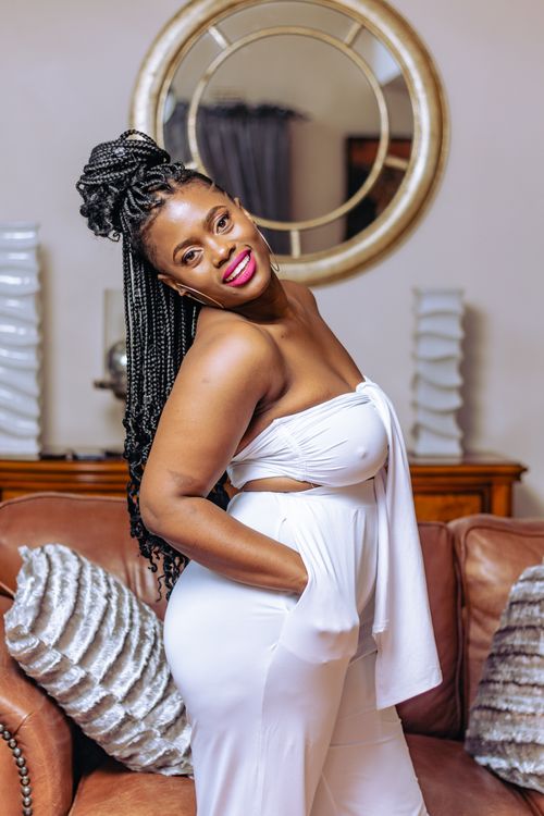 Free Elegant portrait of a black woman posing in white attire with a confident smile indoors. Stock Photo