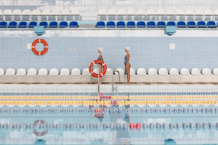 Women Standing By The Poolside Holding A Lifesaver