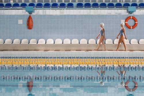 Two Female Swimmers Walking near the Swimming Pool