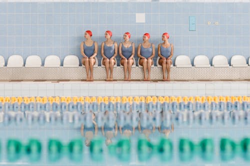 Women in a Swimsuit Uniform Sitting Beside a Pool