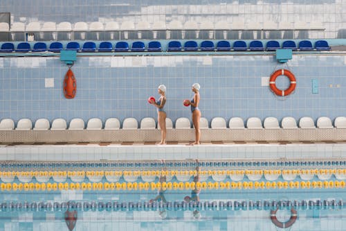 Women in Bikini Standing on Pool Ledge Holding Red Balls