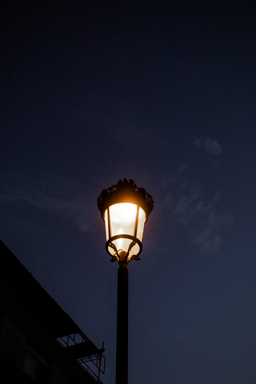Free A classic street lamp illuminated against a dusky evening sky, capturing a serene urban atmosphere. Stock Photo