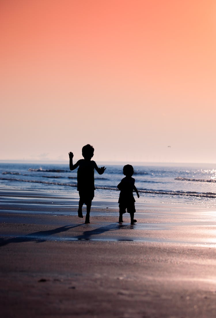 Silhouettes Of Kids Running At The Beach