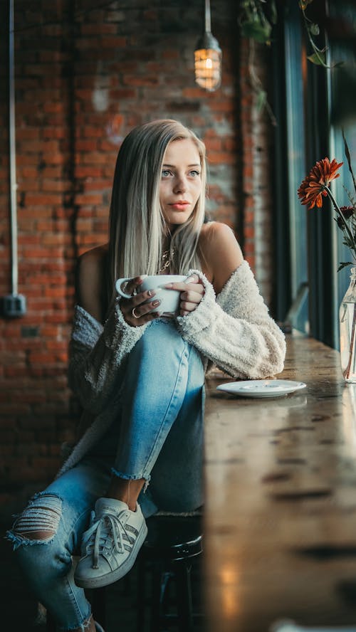 Free Woman Sitting while Holding a Cup Stock Photo