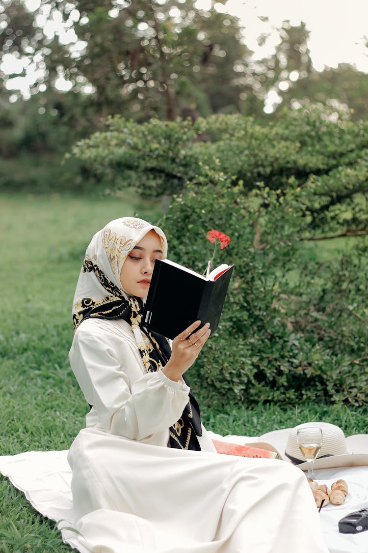Photo Of A Woman With A Headscarf Reading A Black Book