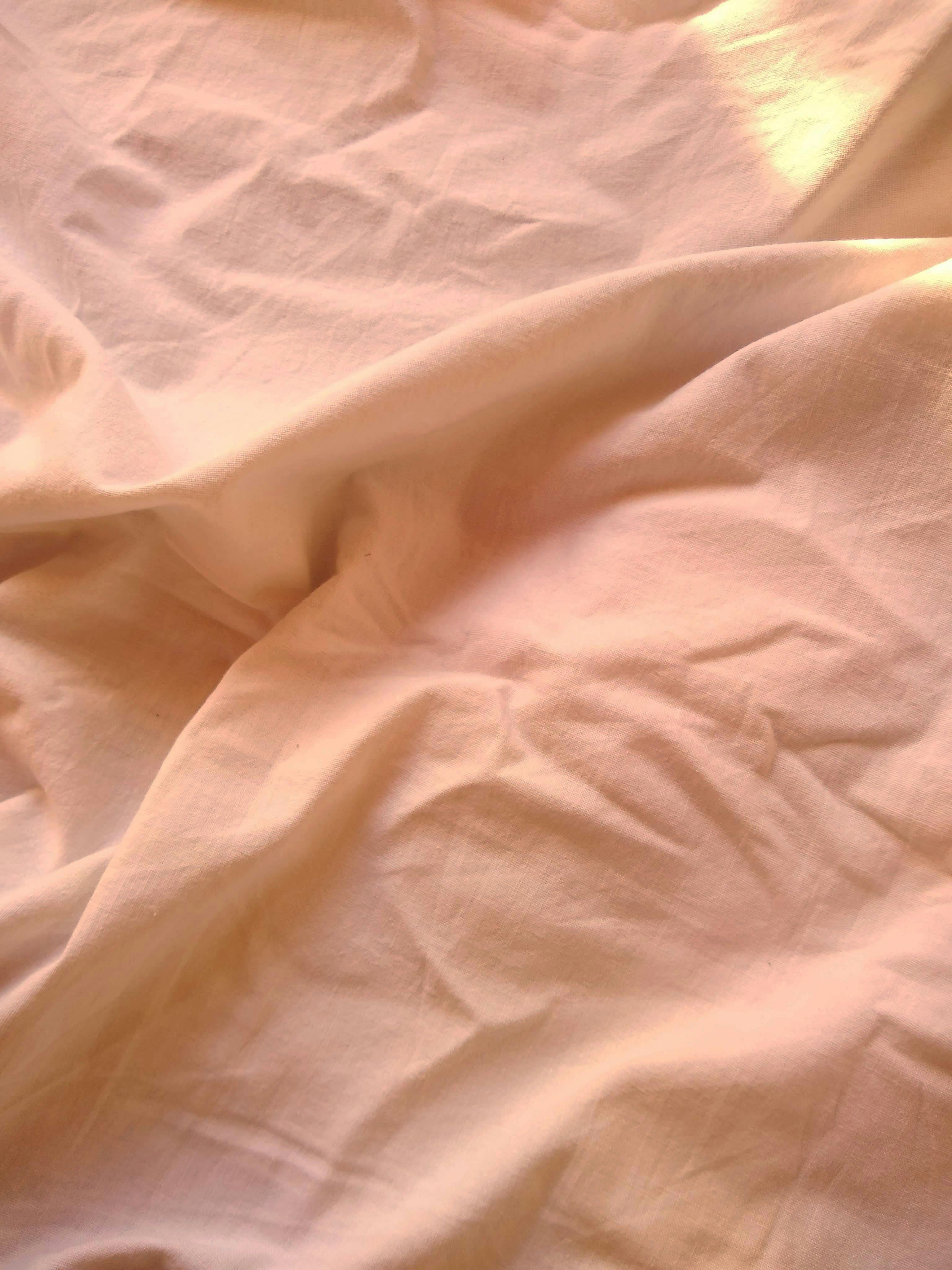 A detailed close-up of peach-colored fabric with gentle creases and elegant texture.