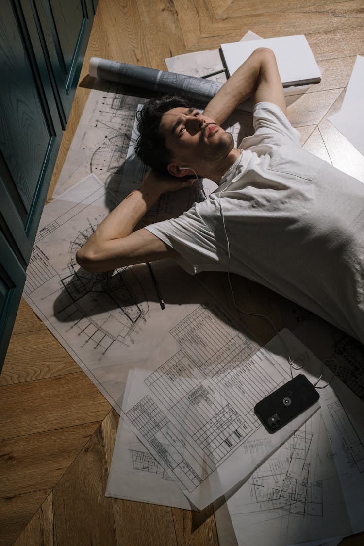 Adult Man Laying Down On Floor Among Drawings