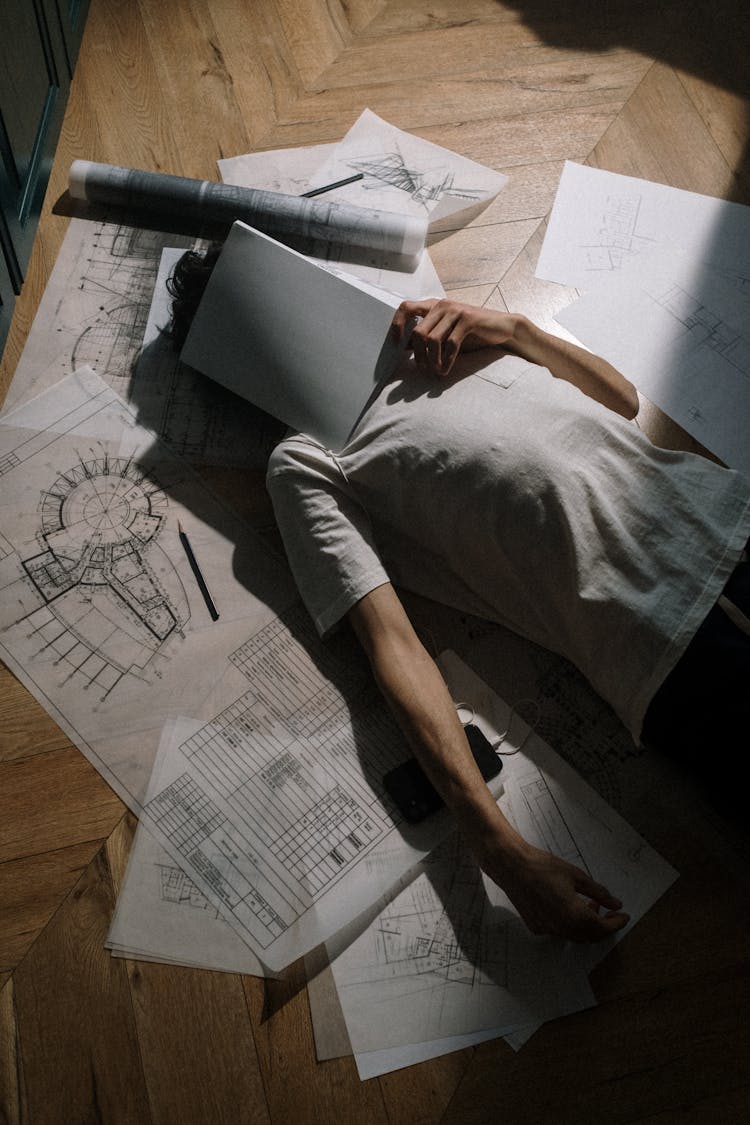 Adult Man Laying Down On Floor With Book On Head