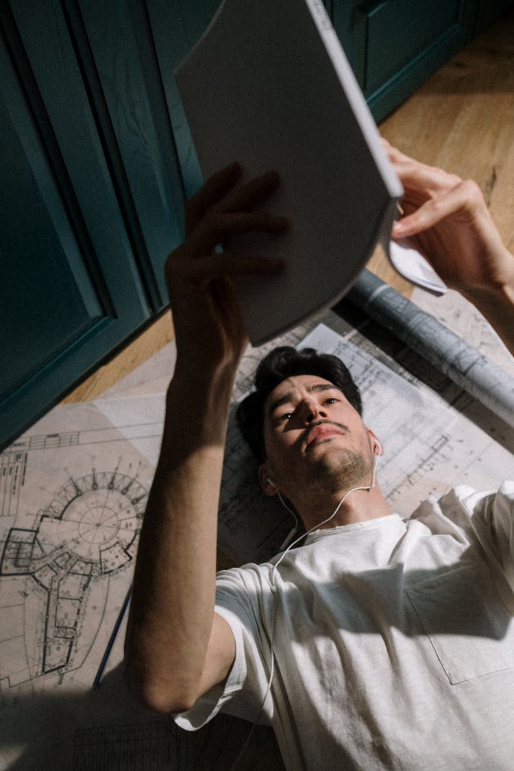 Adult Man Laying Down On Floor And Looking At Book