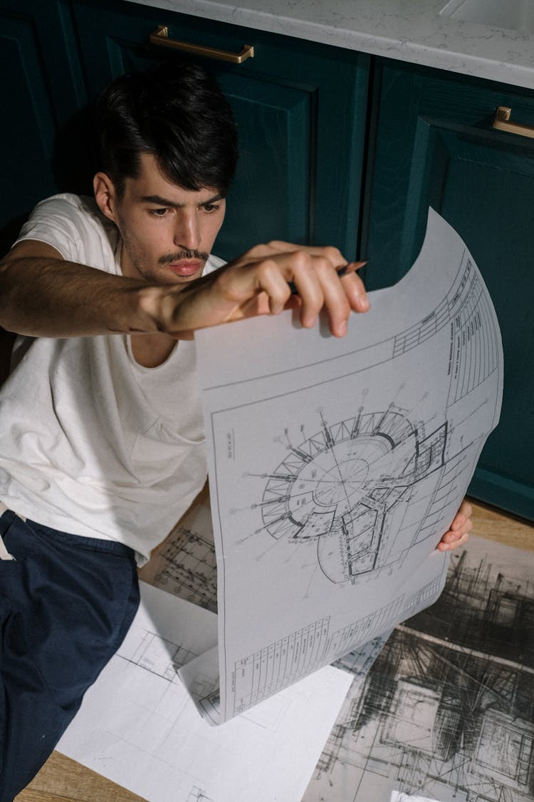 Adult Man Sitting On Floor And Looking At Drawing