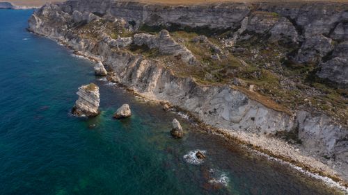 Free A stunning aerial view of rugged cliffs and turquoise water along the coastline. Stock Photo