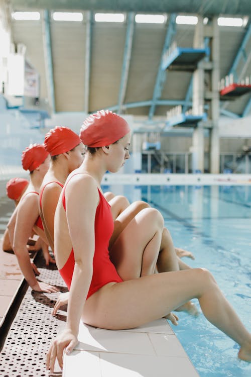 Women in Red Bathing Suits Sitting by the Poolside