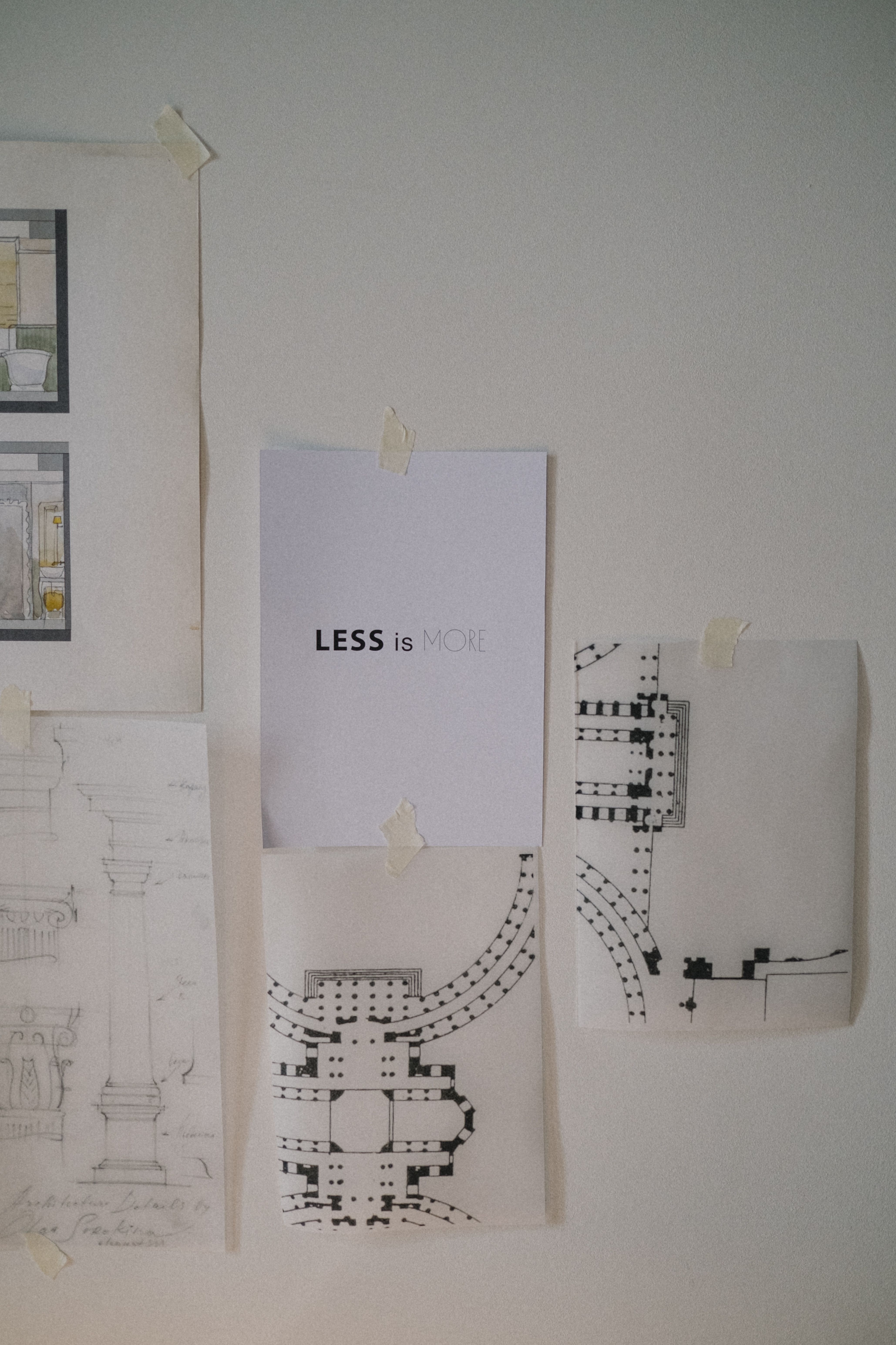 Series of architectural sketches and a 'Less is More' poster taped to a wall.