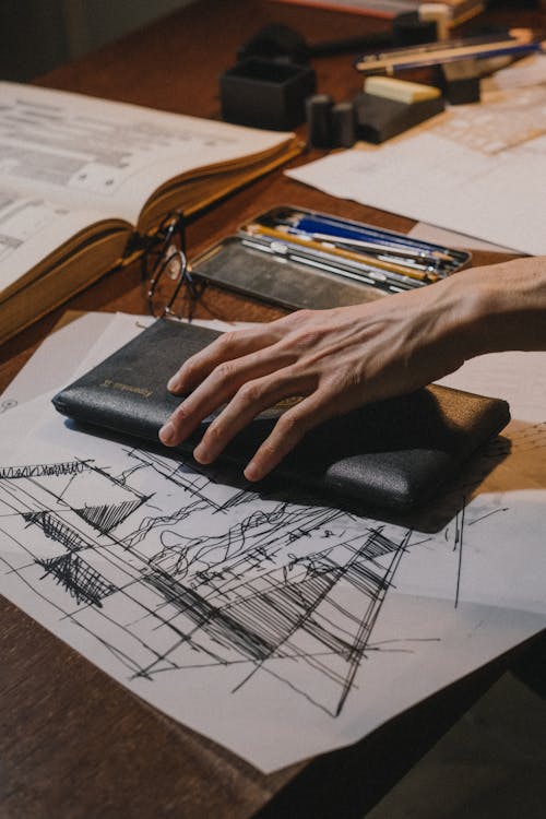 Close up on mans hand on deck with drawing accessories