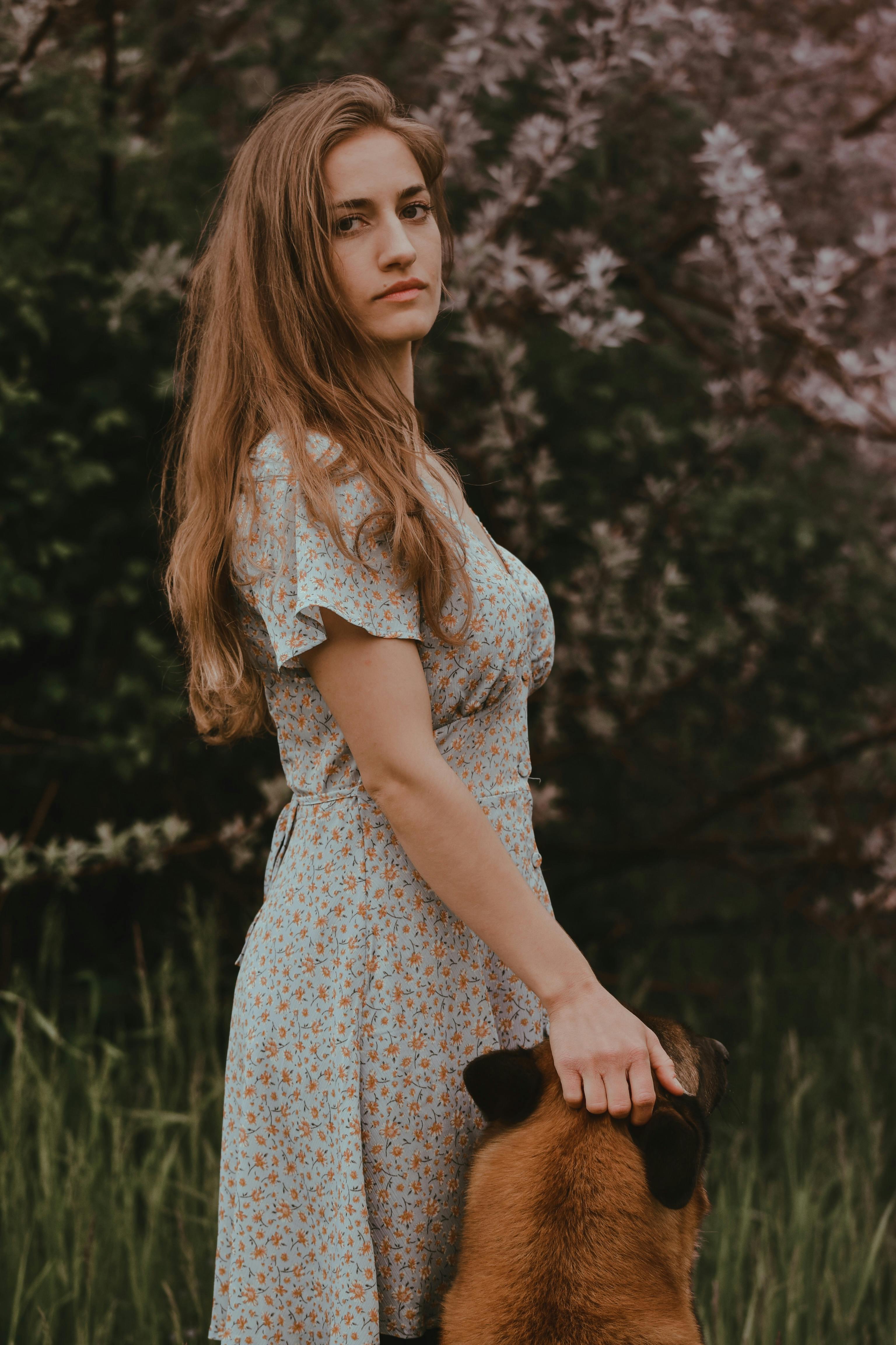 beautiful woman wearing a floral dress posing with her pet dog