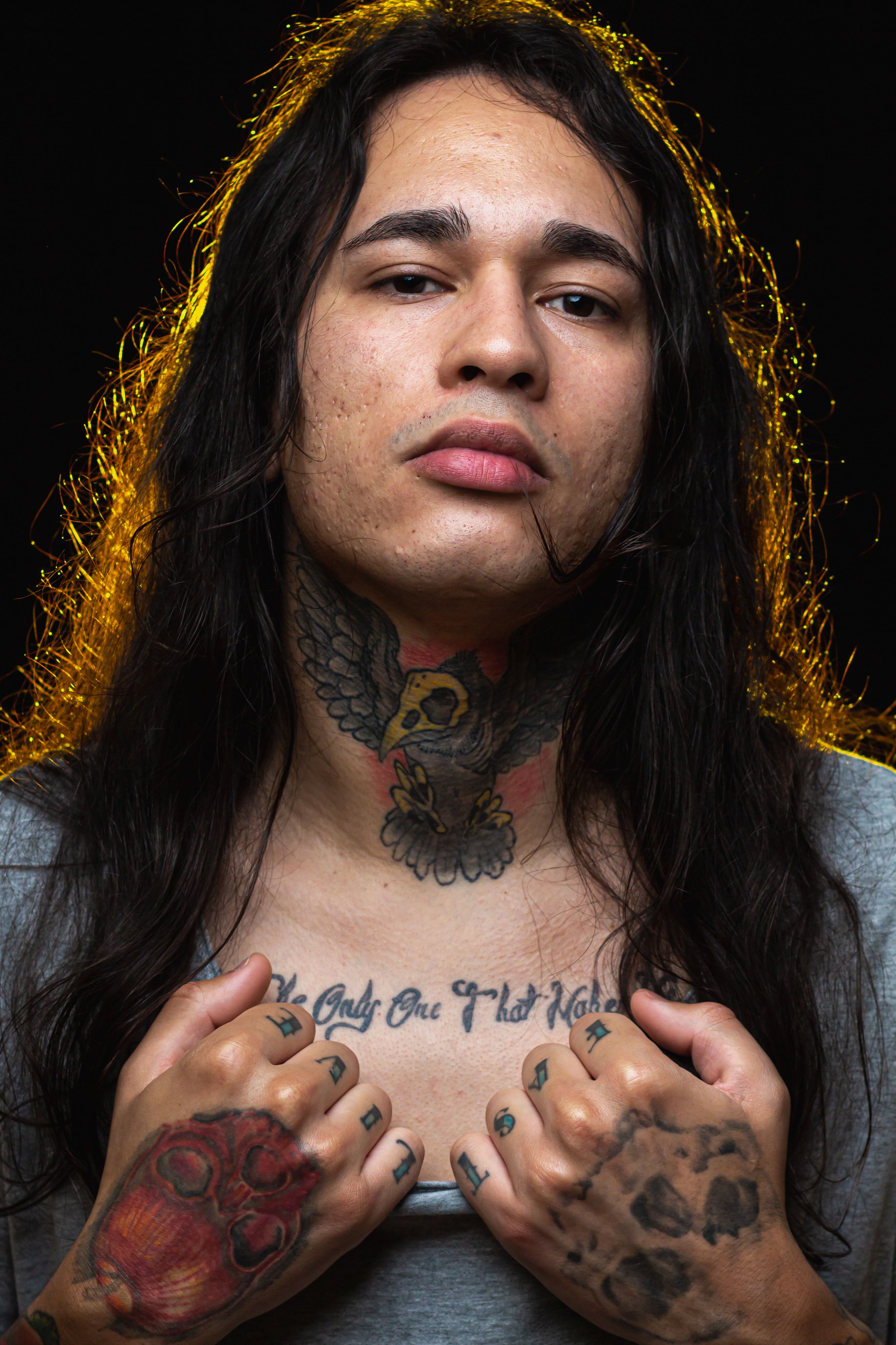 Close-up portrait of a tattooed man with long hair and intense look, studio lighting.