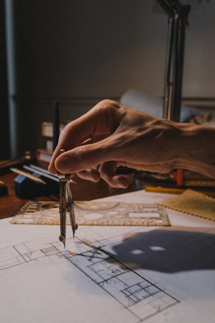 Person Making Architectural Drawing With Divider