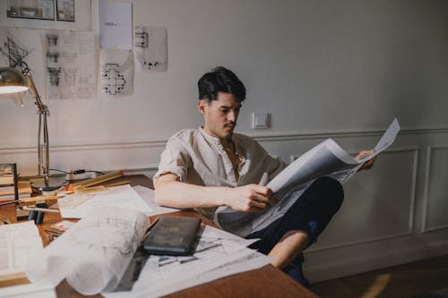 Adult man sitting on chair ans looking at paper in hands