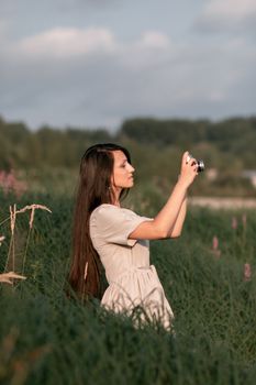 Stylish woman in a brown dress taking photos amid a lush green countryside