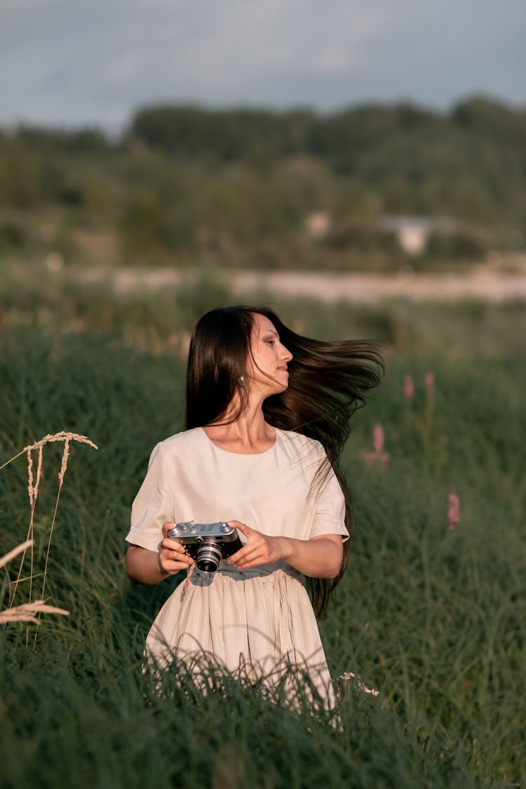 A Woman Swaying Her Hair While Standing On A Grass Field