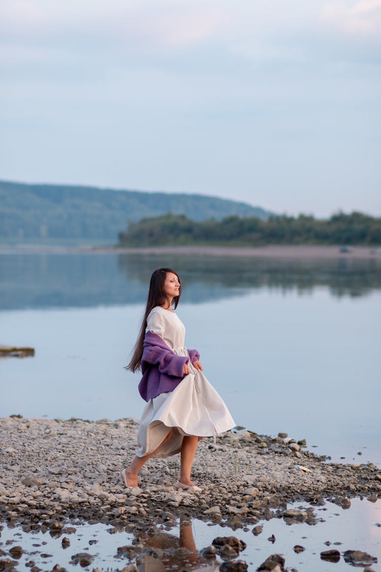 Woman In White Dress And Purple Shawl Standing On Lake Shore