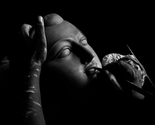 Free Black and white close-up of a sculptor shaping a clay mask, capturing the artistry and detail. Stock Photo