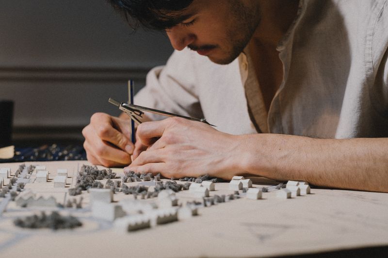 Hands adjusting pieces on a white architectural model