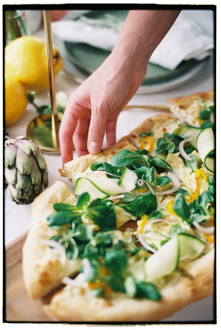 Hand Reaching For Piece Of Pizza With Herbs