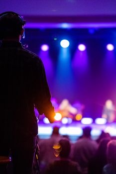 Silhouette of a person at a concert with colorful stage lights.