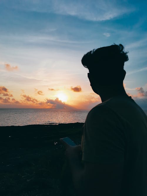 Silhouette of Man on Sea Shore at Sunset