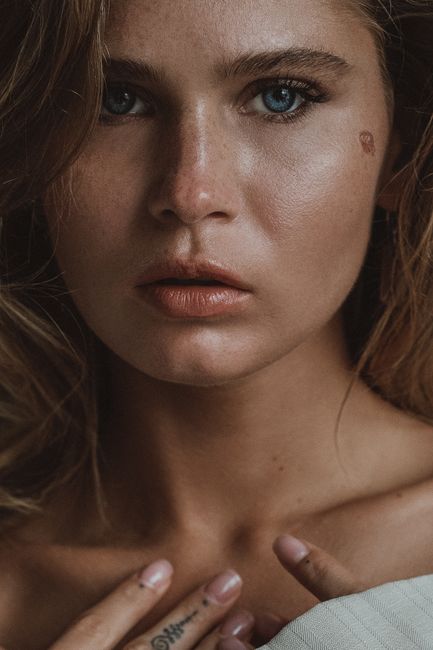 Intimate close-up portrait of a thoughtful woman with expressive blue eyes and long blond hair.