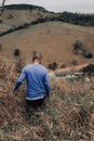 Man in Blue Long Sleeve Shirt and Black Pants Standing on Brown Grass Field