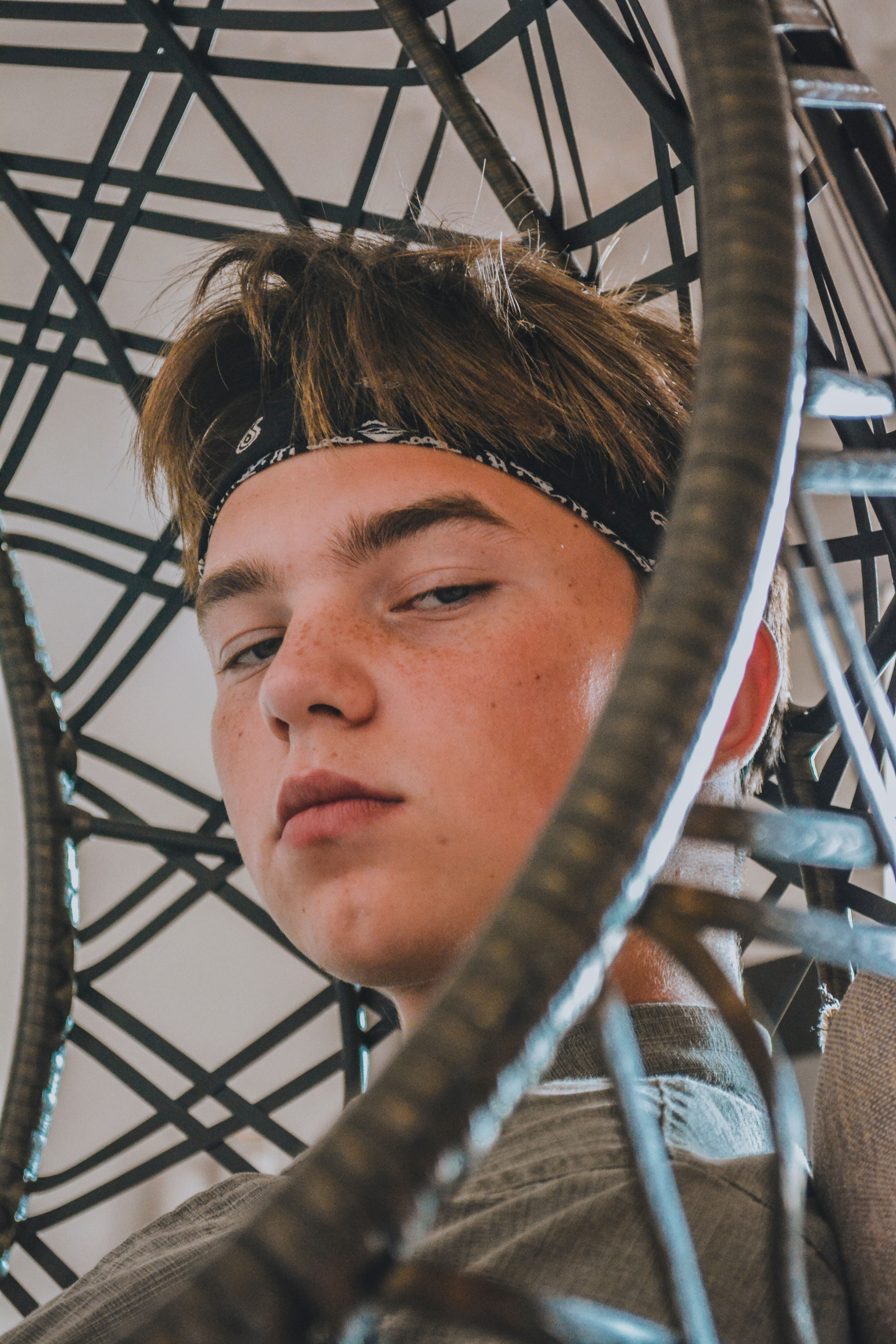 Close-up of a teenager wearing a bandana, posing confidently amidst an artistic metal structure.