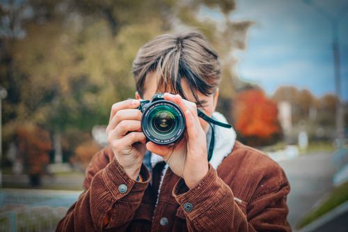 Free Close-up of a photographer taking a picture outdoors during fall. Stock Photo