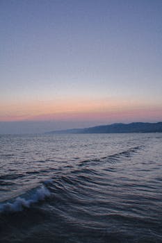 Peaceful sunset over Santa Monica Beach with gentle ocean waves and vibrant skyline.