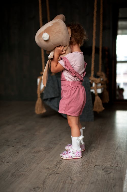 Photo of a Girl in Pink Clothes Holding a Stuffed Toy