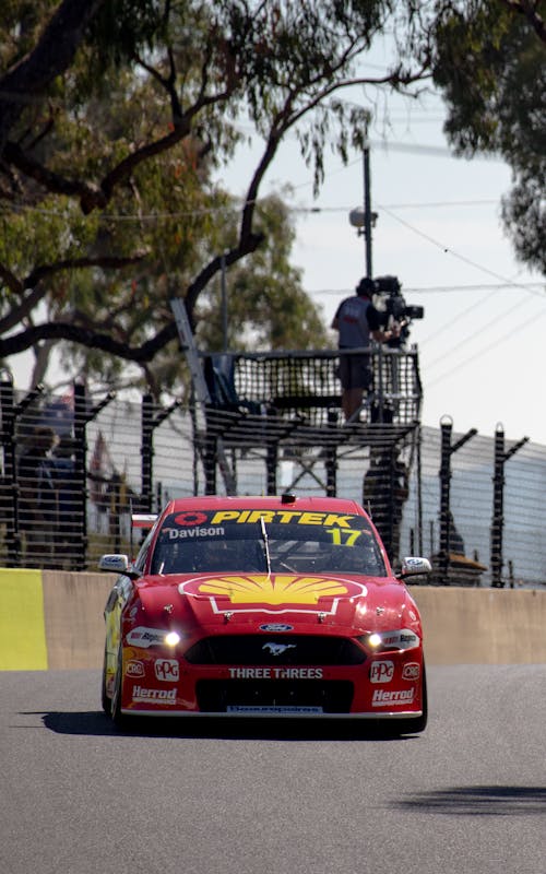 Red Racing Car on the Road Near Wired Fence