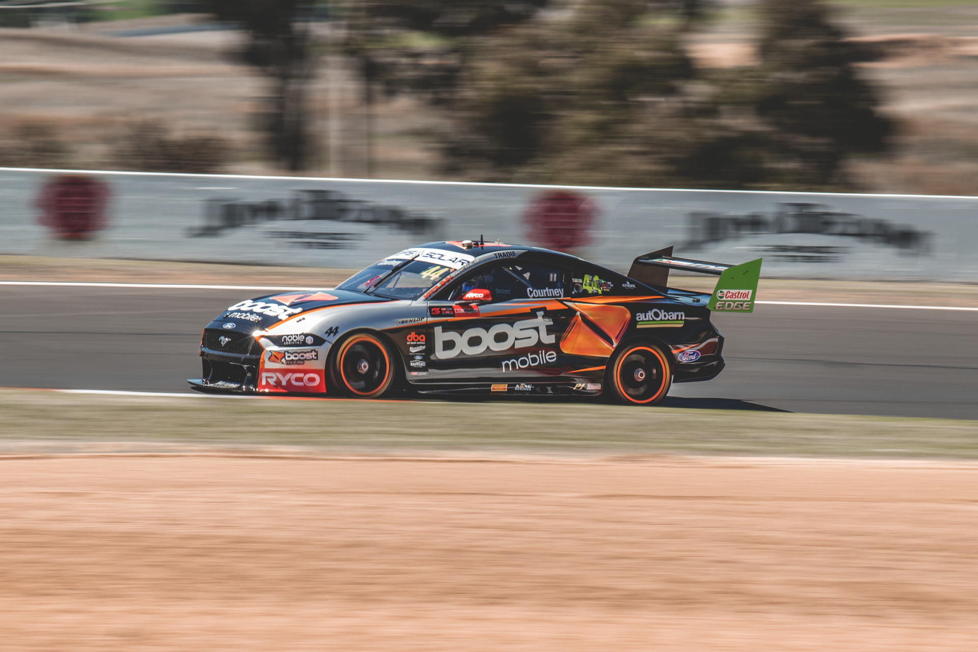Racing car speeding on Mount Panorama track in Australia, capturing motion and excitement.