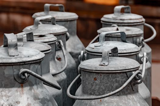 A close-up of vintage metal milk cans arranged in an outdoor rustic setting.