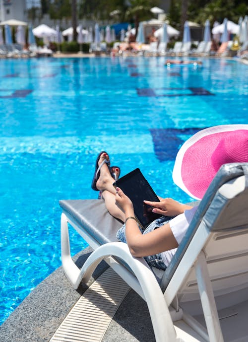 A Woman Sitting by the Poolside Using a Tablet Computer